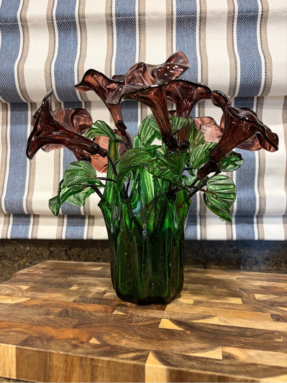 Vintage green swing glass vase with purple lily trumpet flowers.